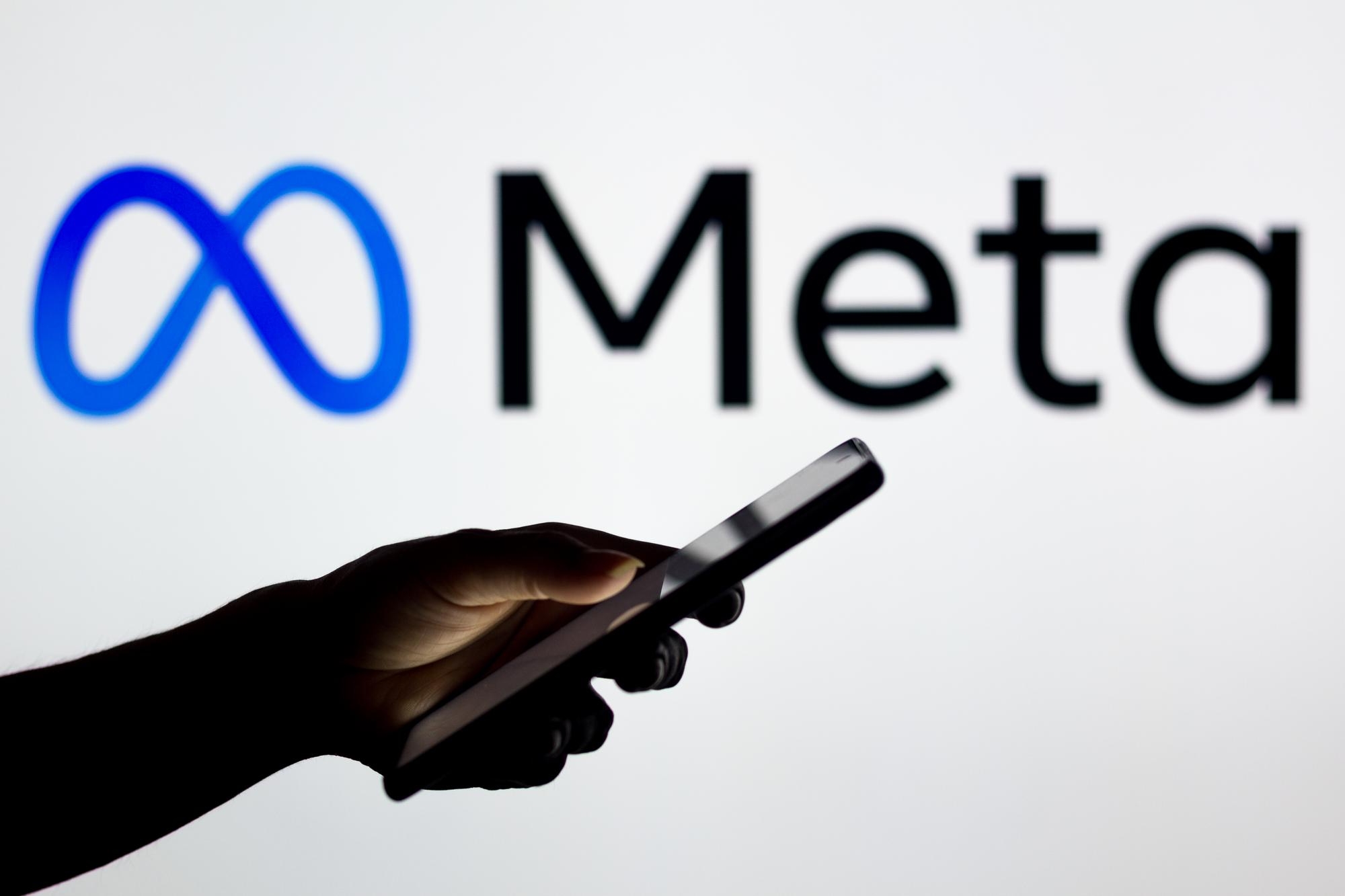 Logo da Meta e uma mão com smartphone